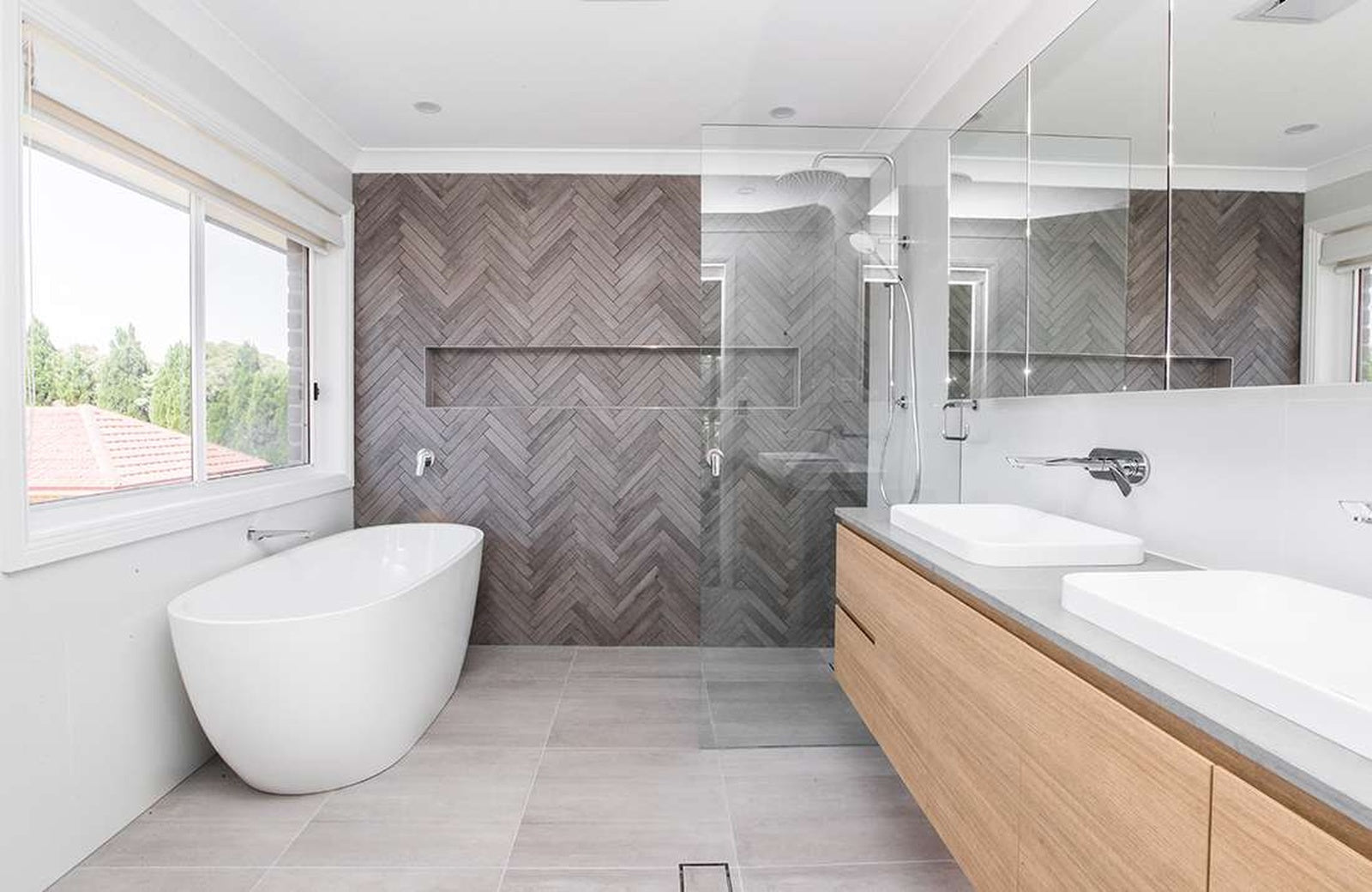 Modern bathroom with wooden vanity, freestanding bathtub, and glass shower enclosure.